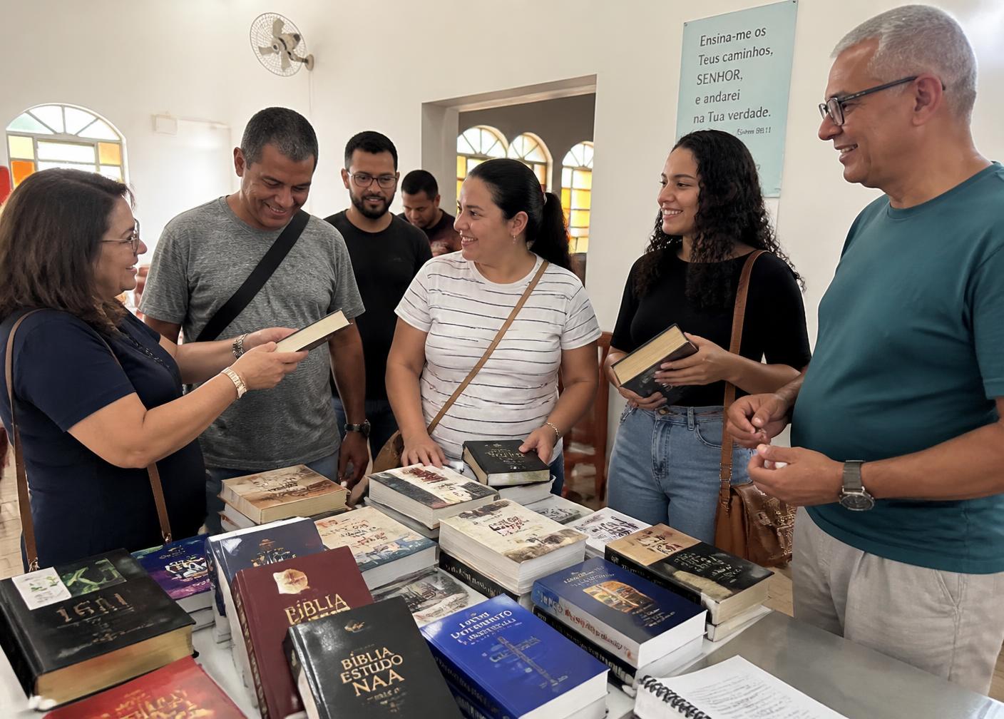 Membros de igreja escolhendo livros e Bíblias em uma mesa